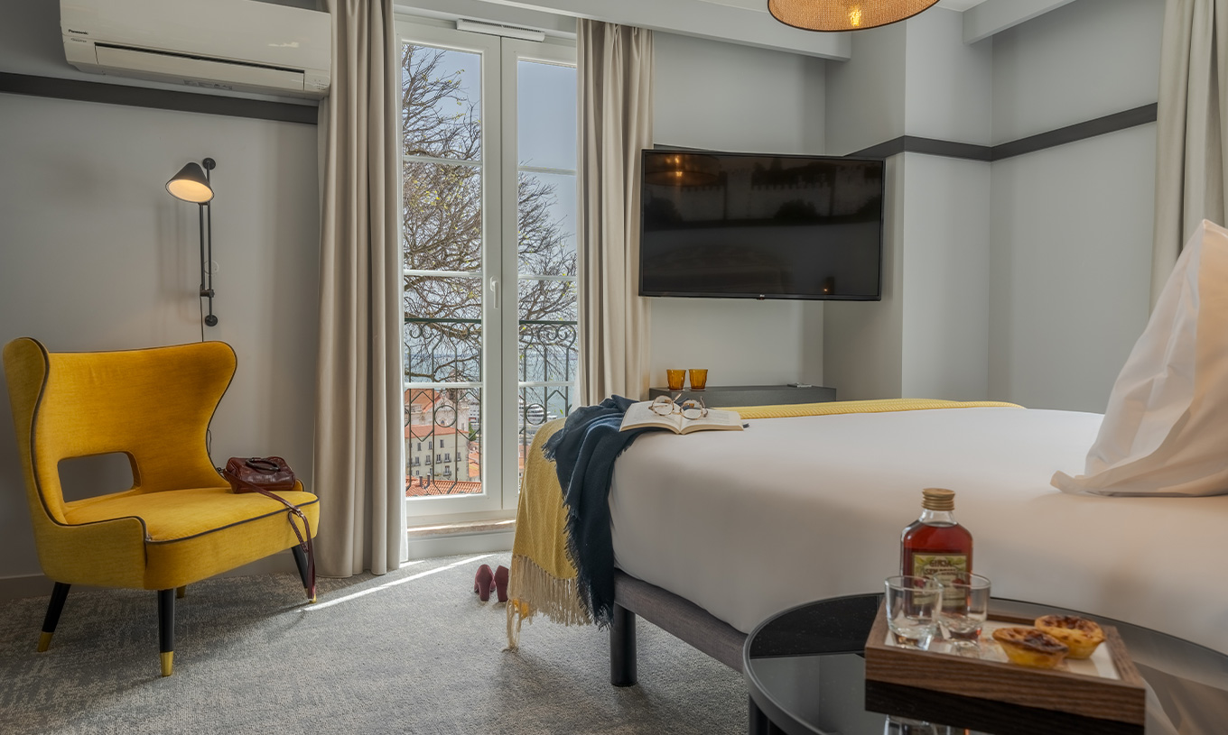 Das Large Family Premium der Pousada Alfama hat einen TV, einen Sessel und ein Fenster mit Blick auf den Miradouro