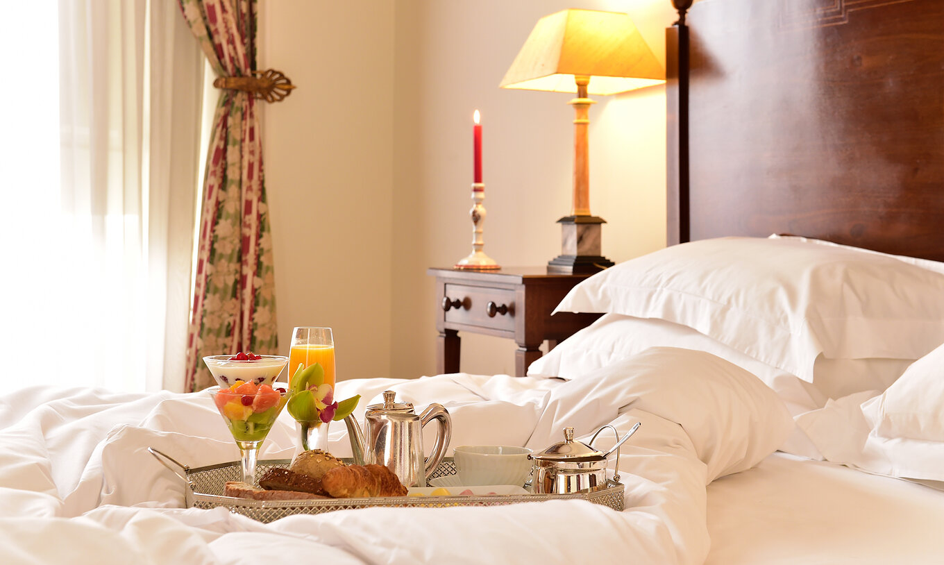 Im Familienzimmer der Pousada Palácio Queluz genießen Sie ein Frühstück im Bett mit Obstsalat und Croissants