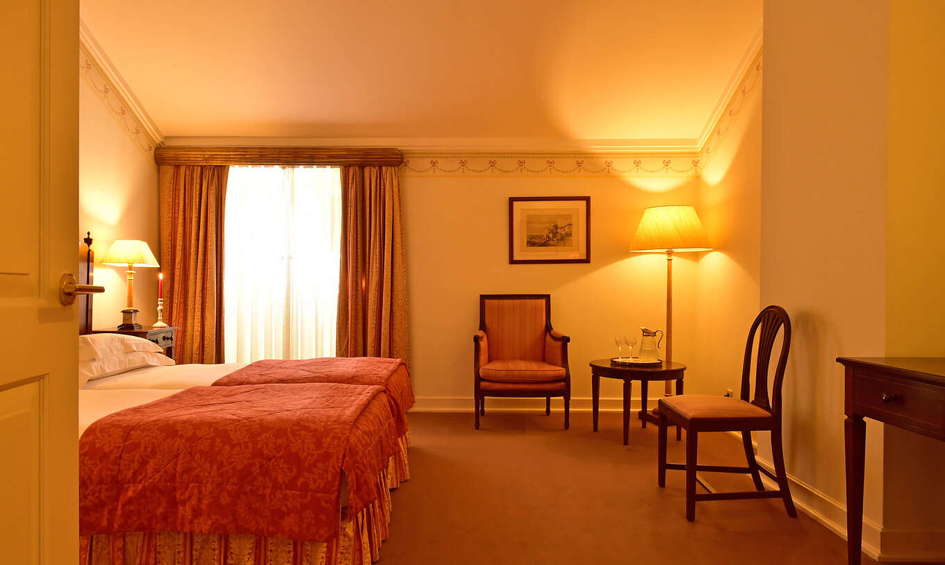 Das klassische Zimmer der Pousada Palácio Queluz hat viel Platz um das Bett, mit zwei Stühlen und einem Fenster