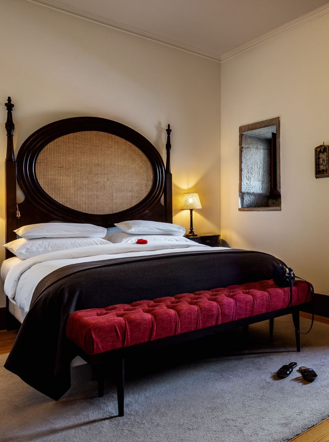 Der klassische Raum der Pousada Mosteiro Guimarães hat ein Doppelbett mit einem Kopfteil aus dunklem Holz und Stroh