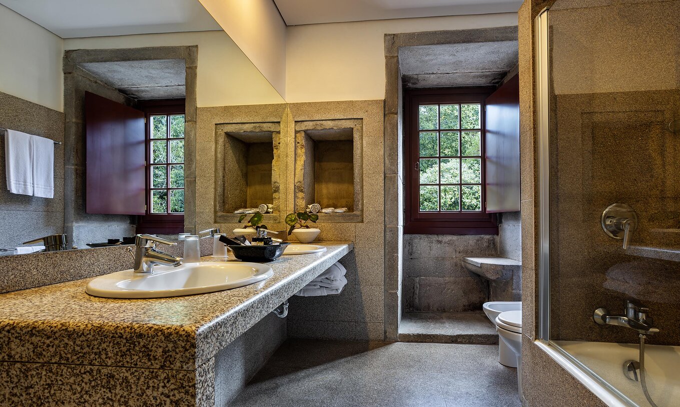 Die Historische Suite der Pousada Mosteiro Guimarães hat ein Badezimmer mit Waschbecken, Fenster, Badewanne und Toilette