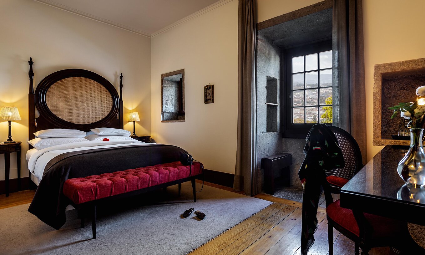 Der historische Superior Raum der Pousada Mosteiro Guimarães hat ein Doppelbett mit einem Kopfteil aus Holz und ein Fenster