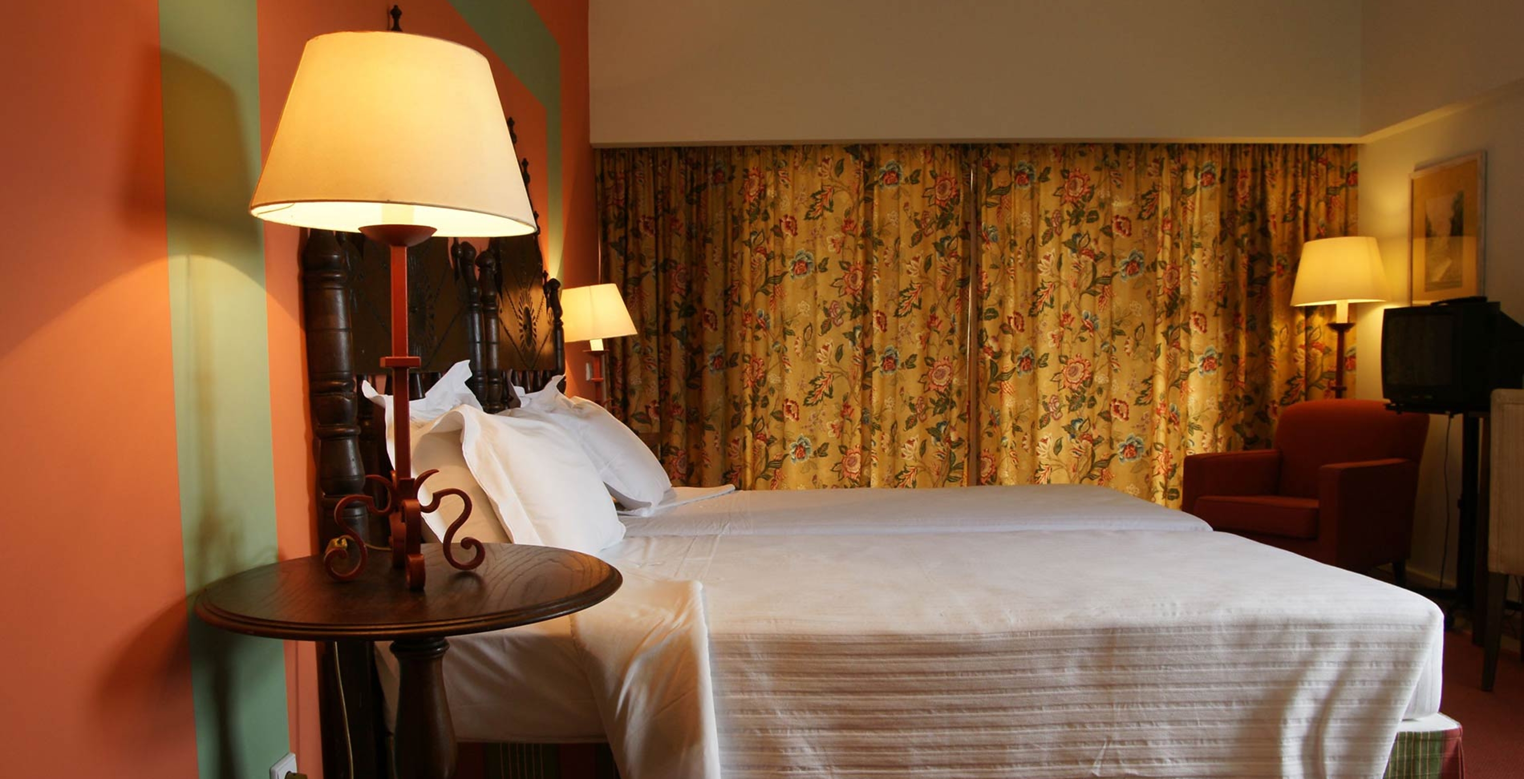 Die Junior Suite der Pousada Valença hat zwei Einzelbetten, einen Nachttisch, einen Sessel und einen Blumenvorhang