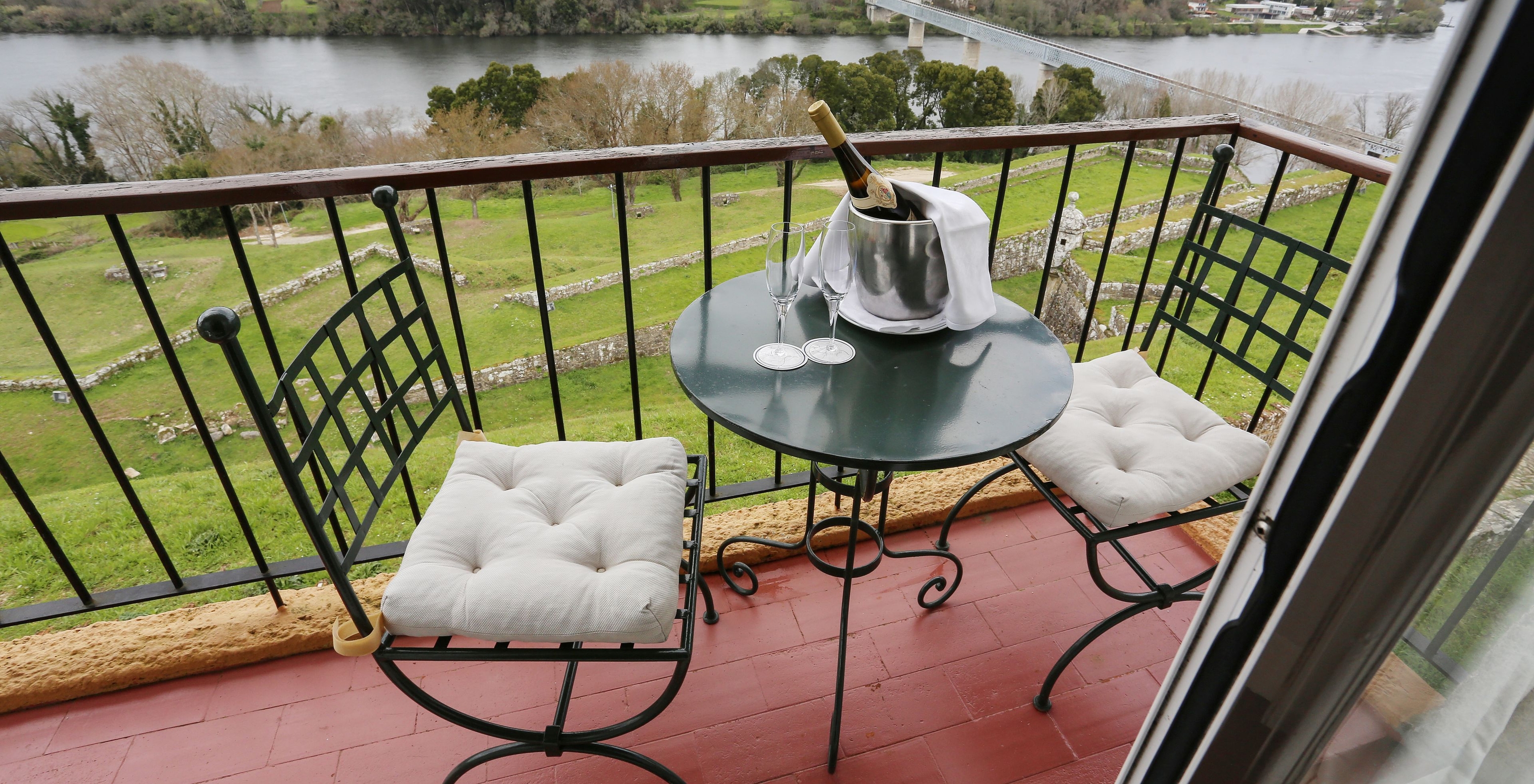 Das Superior Zimmer der Pousada Valença hat einen Balkon mit Tisch, zwei Stühlen, Champagner und Blick auf den Fluss