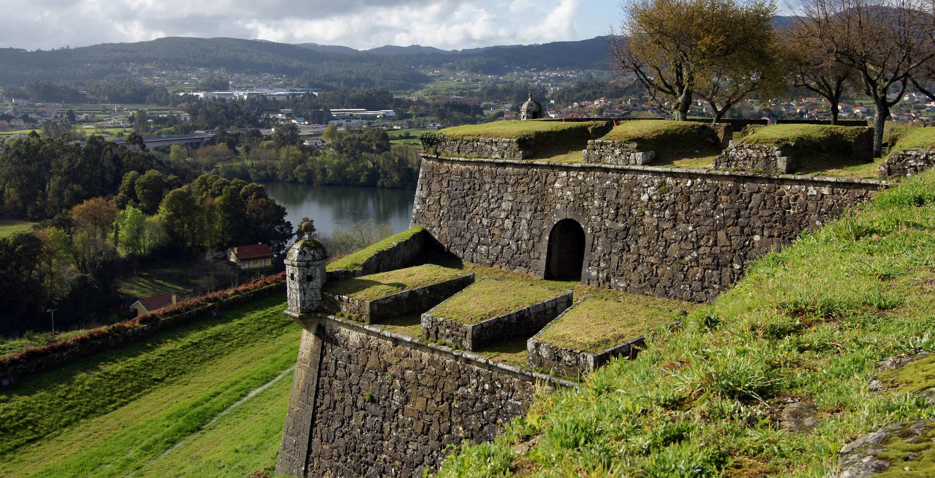 Blick auf eine alte Mauer der Pousada Valença, umgeben von Vegetation und einem Fluss