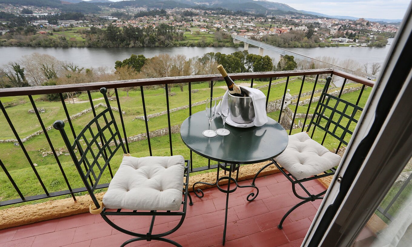 Das Superior Zimmer der Pousada Valença hat einen Balkon mit Tisch, zwei Stühlen, Champagner und Blick auf den Fluss