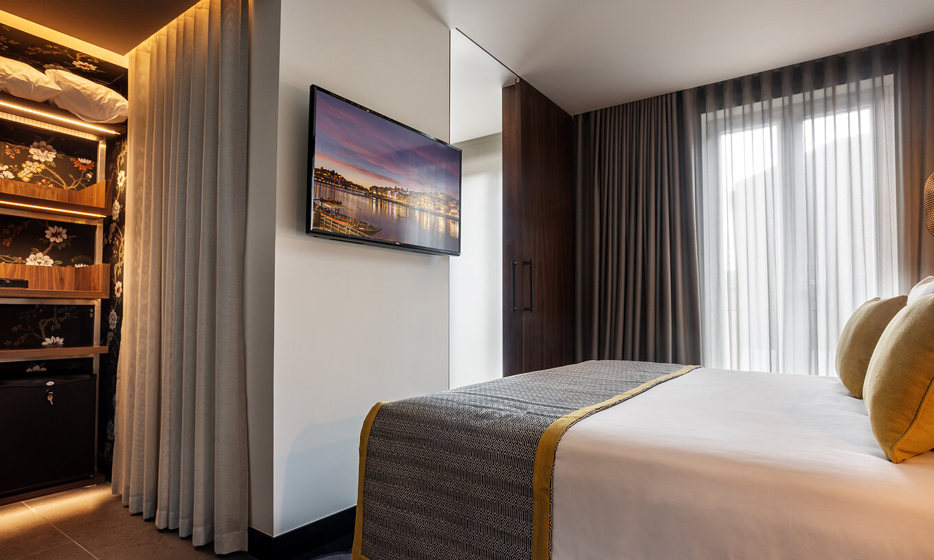 Das Superior Zimmer der Pousada Porto - Rua das Flores hat einen Schrank mit Minibar und einen Fernseher vor dem Bett