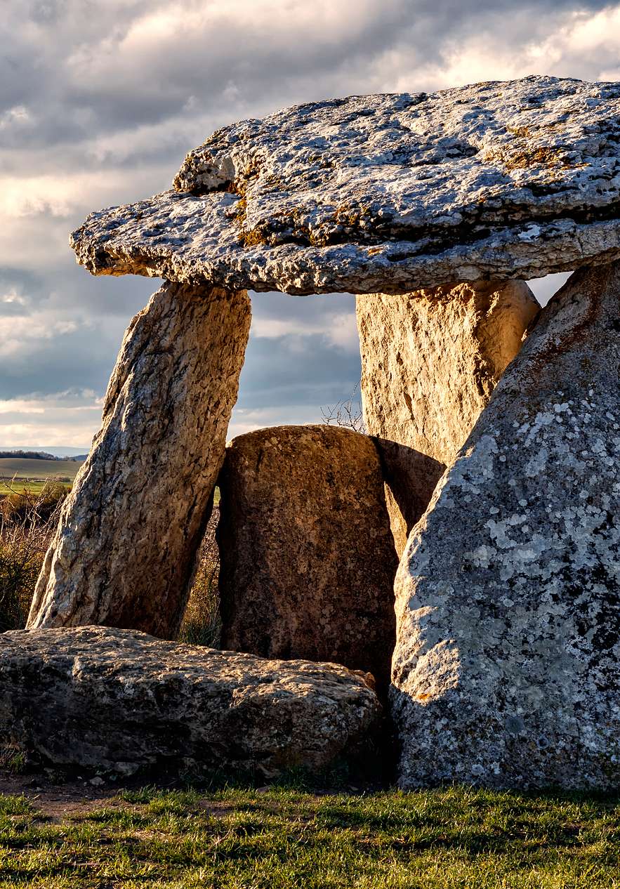 Ancient stone dolmen with massive weathered slabs beneath dramatic clouds in the Alentejo countryside