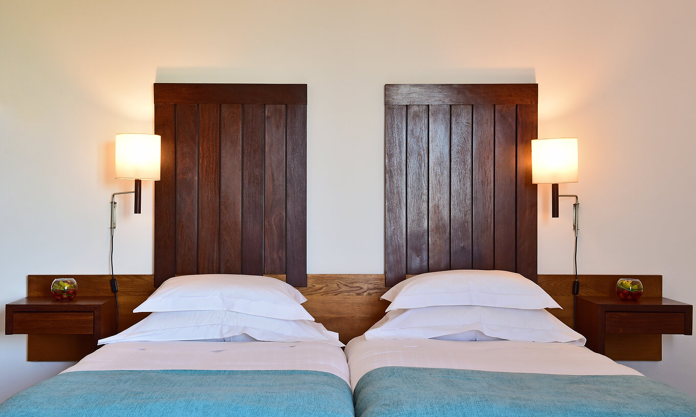 The Large Family Room of the Pousada Castelo Alcácer do Sal has two separate beds, with a blue blanket and a wooden headboard