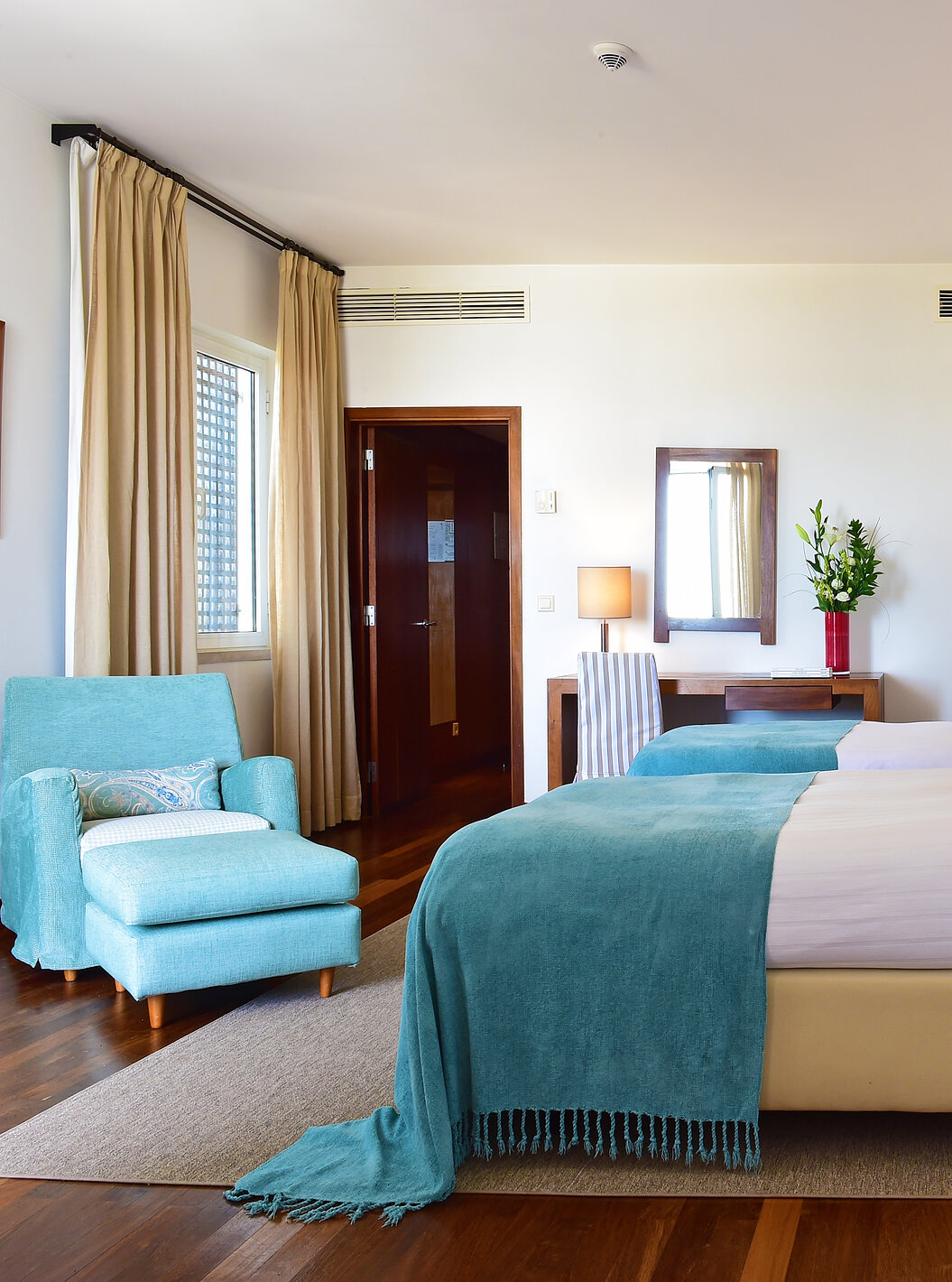 The Large Family Room of the Pousada Castelo Alcácer do Sal has two separate beds, with a blue blanket and an armchair