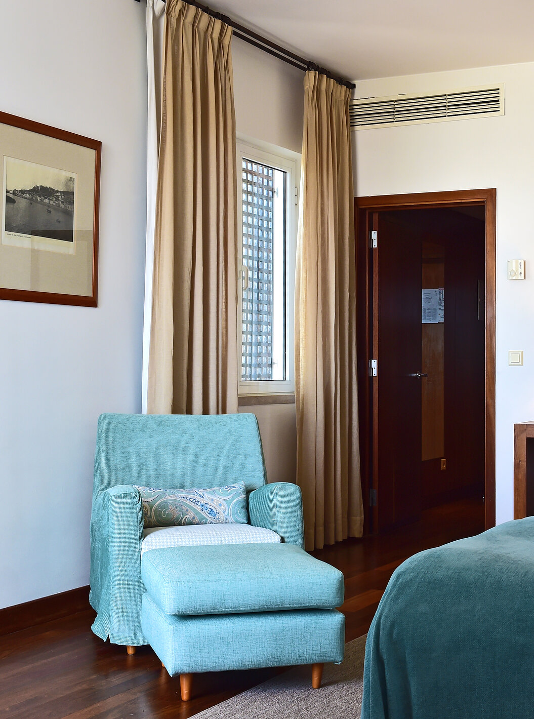 The Superior Family Room of the Pousada Castelo Alcácer do Sal has two separate beds, with a blue blanket and an armchair