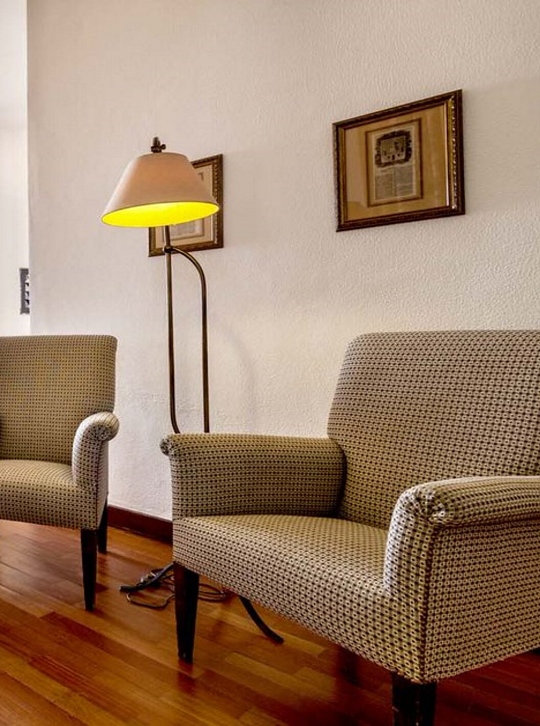 The Large Family Room of the Pousada Castelo Alvito has an entrance hallway with three chairs, a television, and paintings