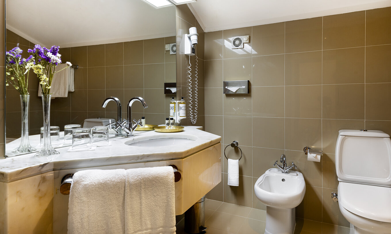 The Classic Room has a sink with towels, mirror, bidet and toilet at Pousada Castelo Estremoz