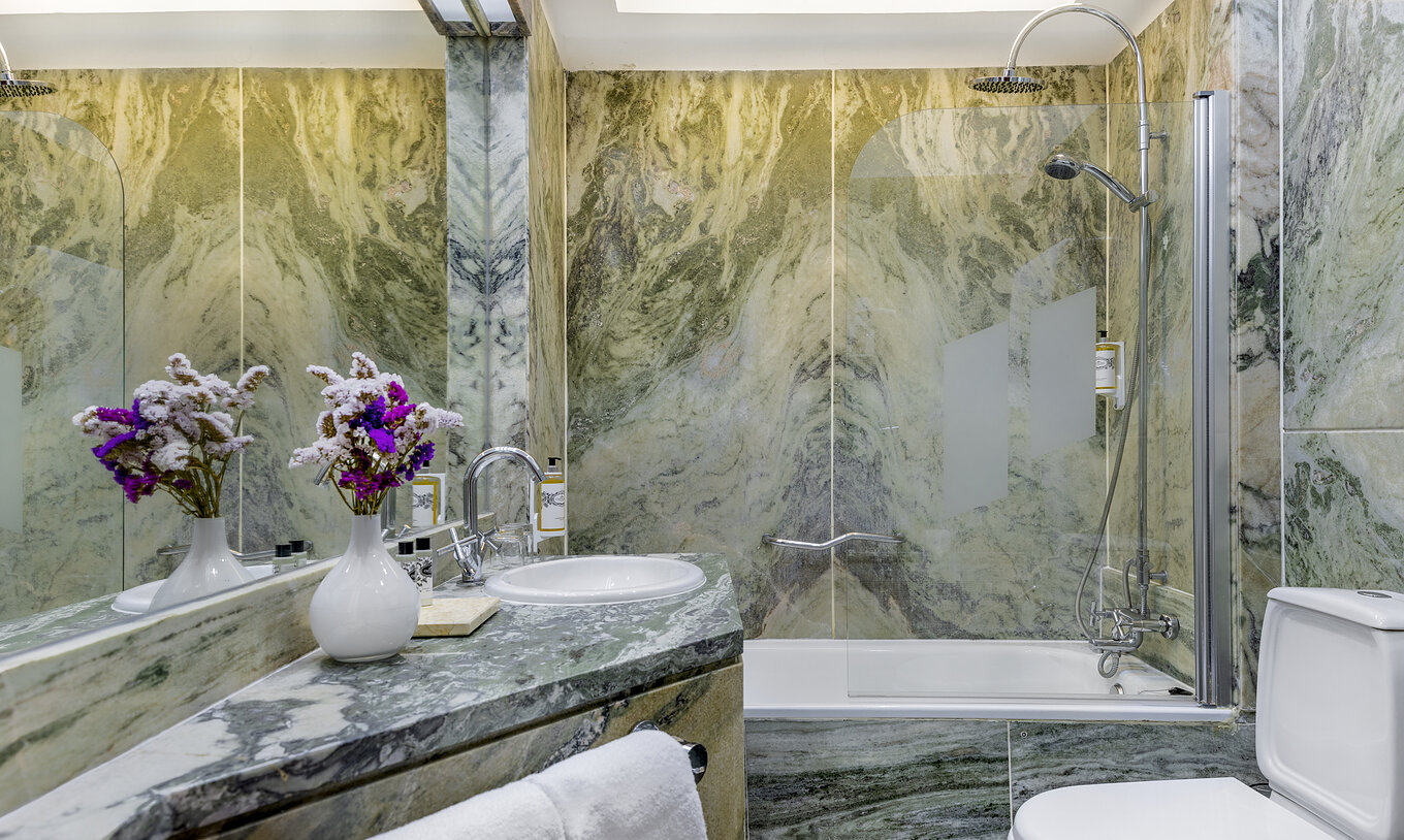 The Junior Suite at Pousada Castelo Estremoz has a bathroom in green tones, with a bathtub with shower and sink