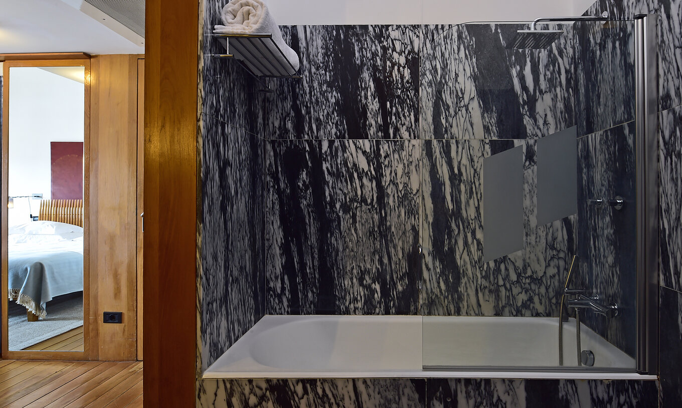 The Superior Family of The Pousada Convento Arraiolos has a dark marble bathroom with a bathtub with a shower