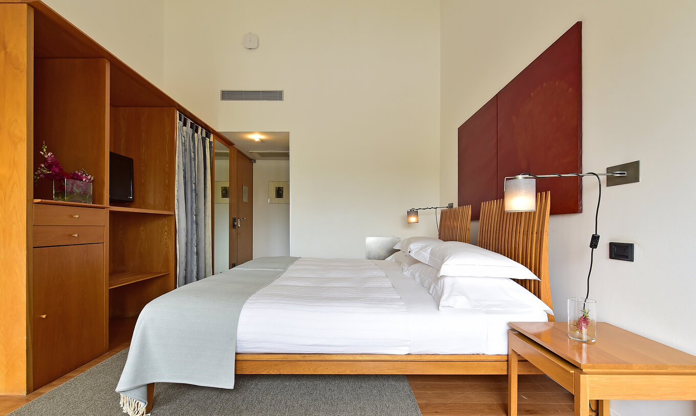 The Superior Family of The Pousada Convento Arraiolos has a bed with a wooden furniture and a television in front