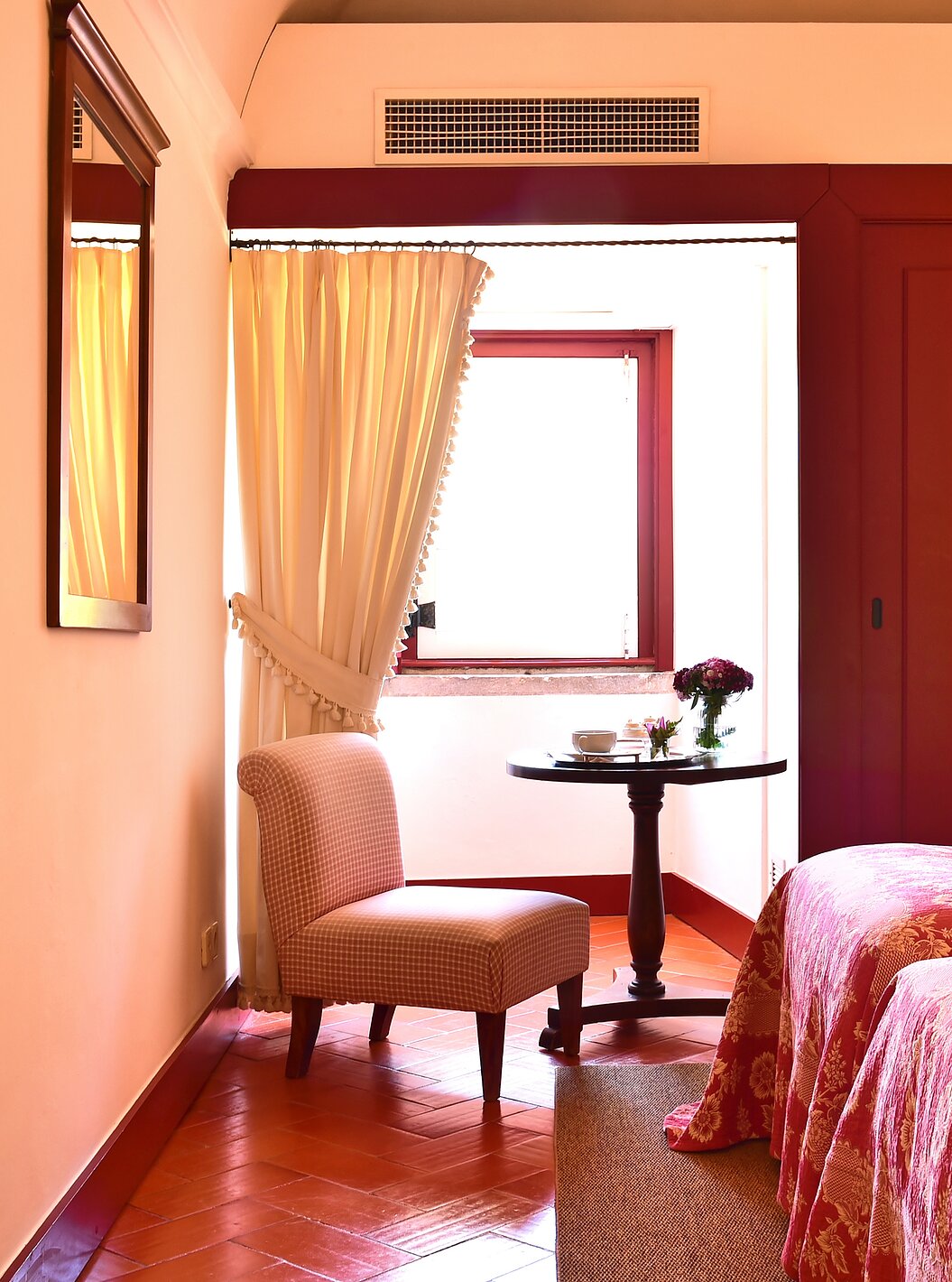 The Classic Room of The Pousada Convento Beja has a side table with a chair by the window of the room