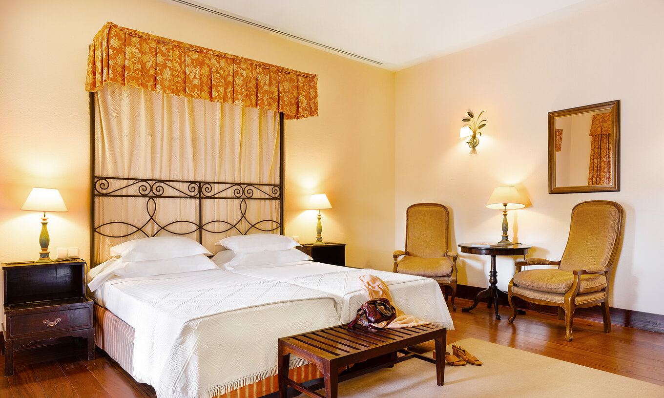 The Family Room of The Pousada Convento Vila Viçosa has two joined beds with a footrest bench and two chairs