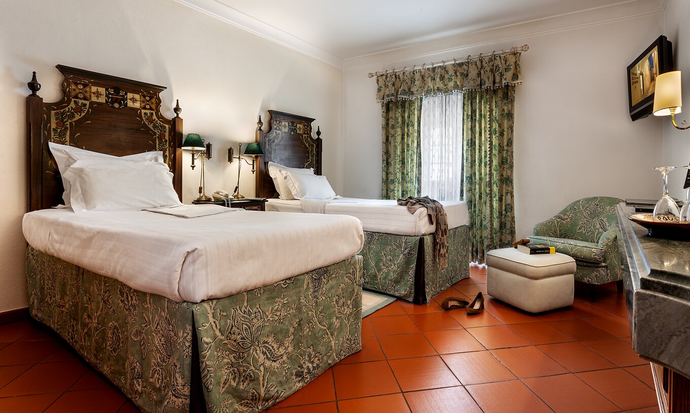 The Terrace Studio of The Pousada Marvão features two separate beds with a floral pattern and a counter