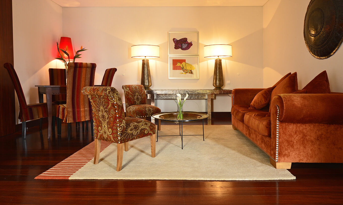 The Special Suite of The Pousada Convento Tavira has a living room with a sofa, two chairs, and a small table for meals