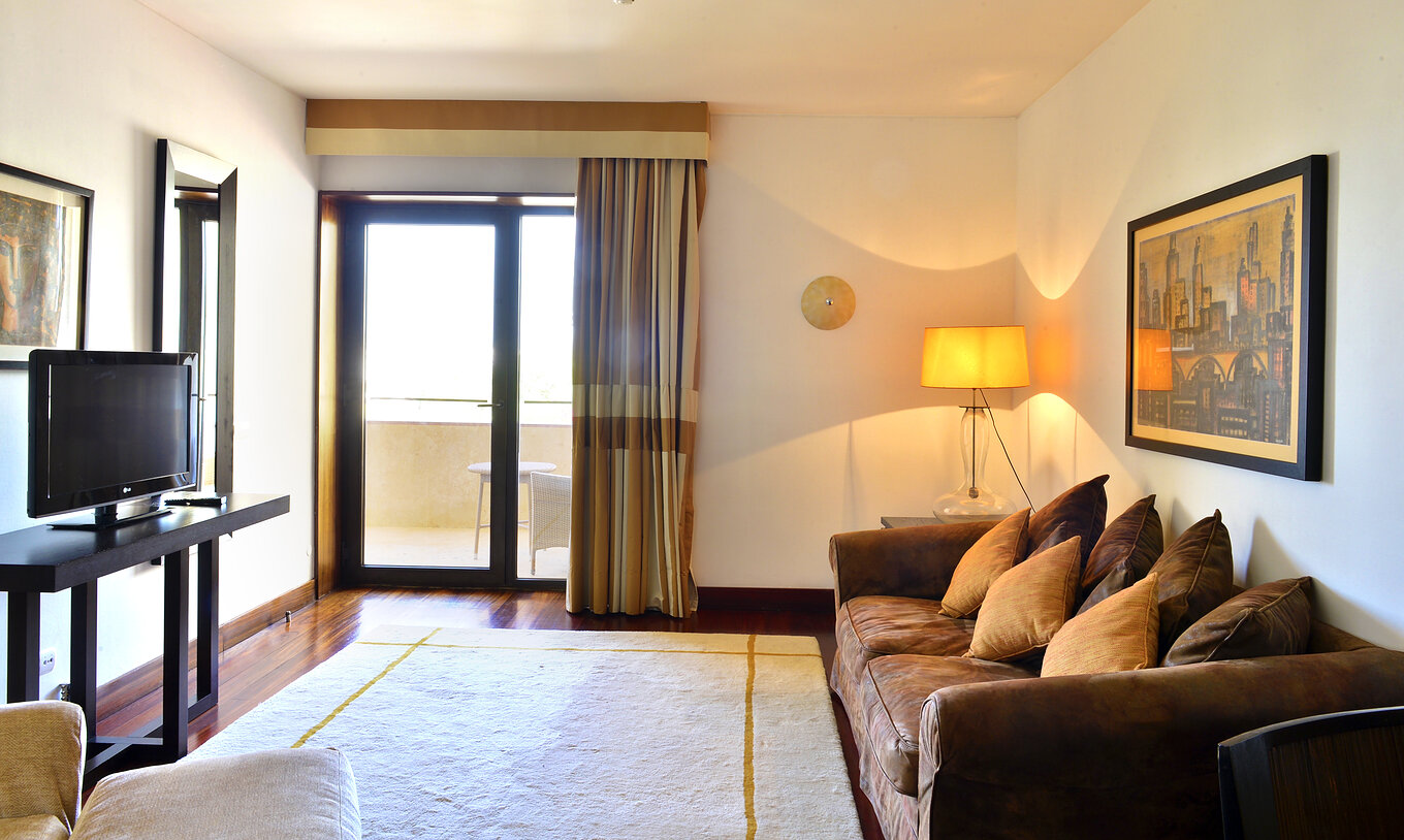 The Standard Suite of The Pousada Convento Tavira has a living room with a sofa, television, window and a balcony