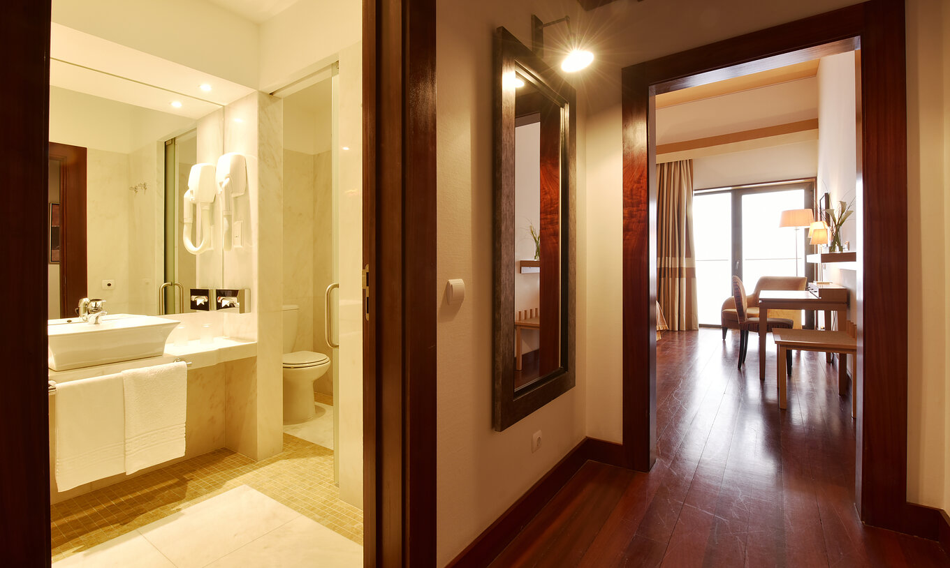 The Superior Room of The Pousada Convento Tavira has a corridor at the entrance with a door to the bathroom with sink 