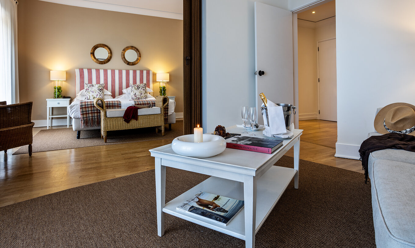The Master Suite of Pousada Sagres has a living room with a table with champagne, a candle, and a book