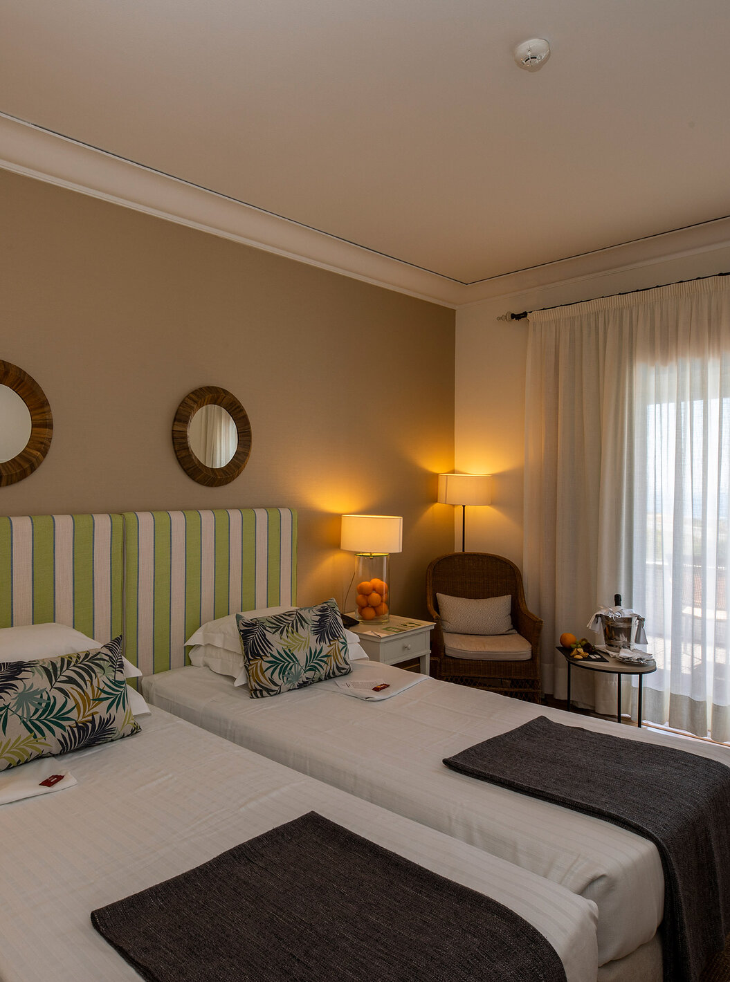 The Superior Room of Pousada Sagres has two beds with striped headboards, two round mirrors, and a balcony