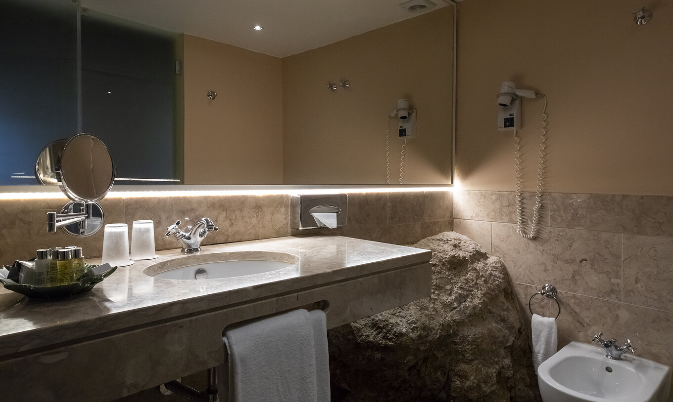 The Suite Cottage at Pousada Castelo Óbidos has a bathroom with mirror, sink, and hairdryer
