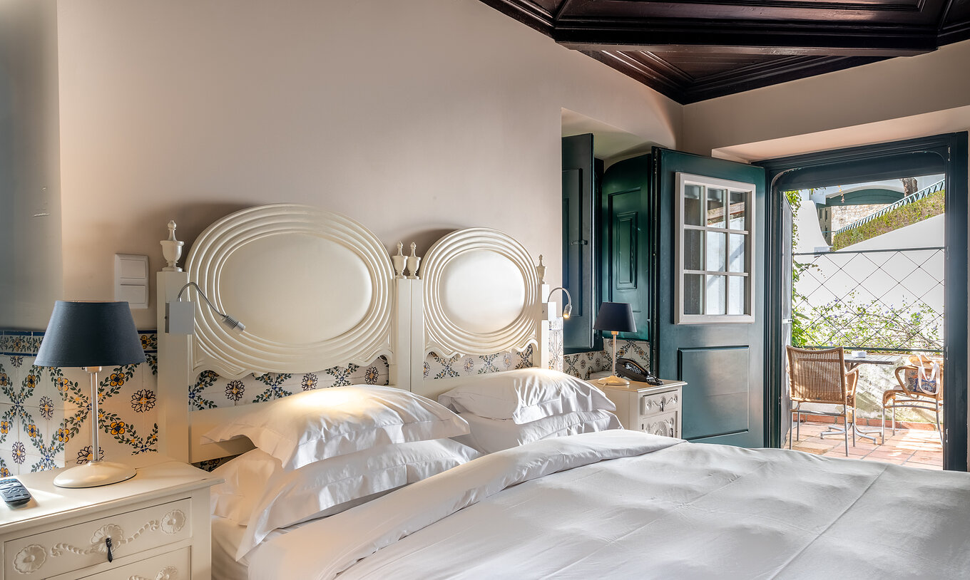 The Superior Room with Balcony Cottage at Pousada Castelo Óbidos has a double bed with a bedside table