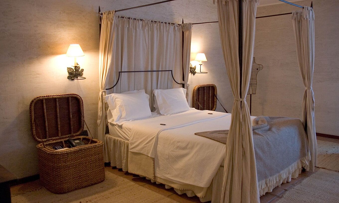 The Classic Room of The Pousada Convento de Belmonte has a double bed and two wicker bedside tables