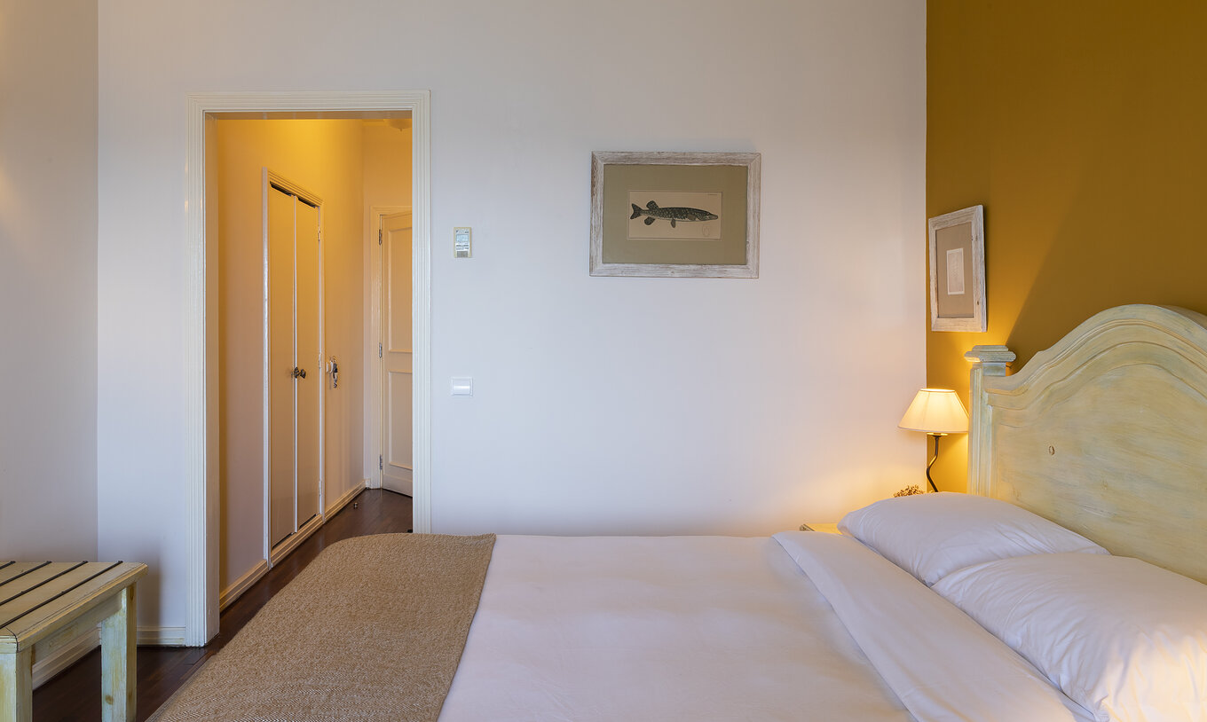 The Superior Ria View of The Ria Inn - Aveiro has a bed, a painting, a closet, and a luggage support area