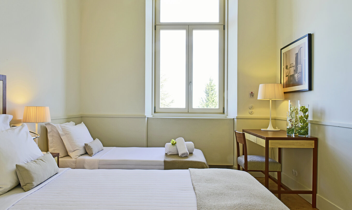 The Classic Room of The Serra da Estrela Inn has a desk, a painting of the old sanatorium, and a TV
