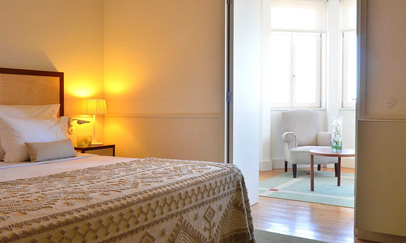 The Junior Suite of The Serra da Estrela Inn has a living room with an armchair and a coffee table, and two windows