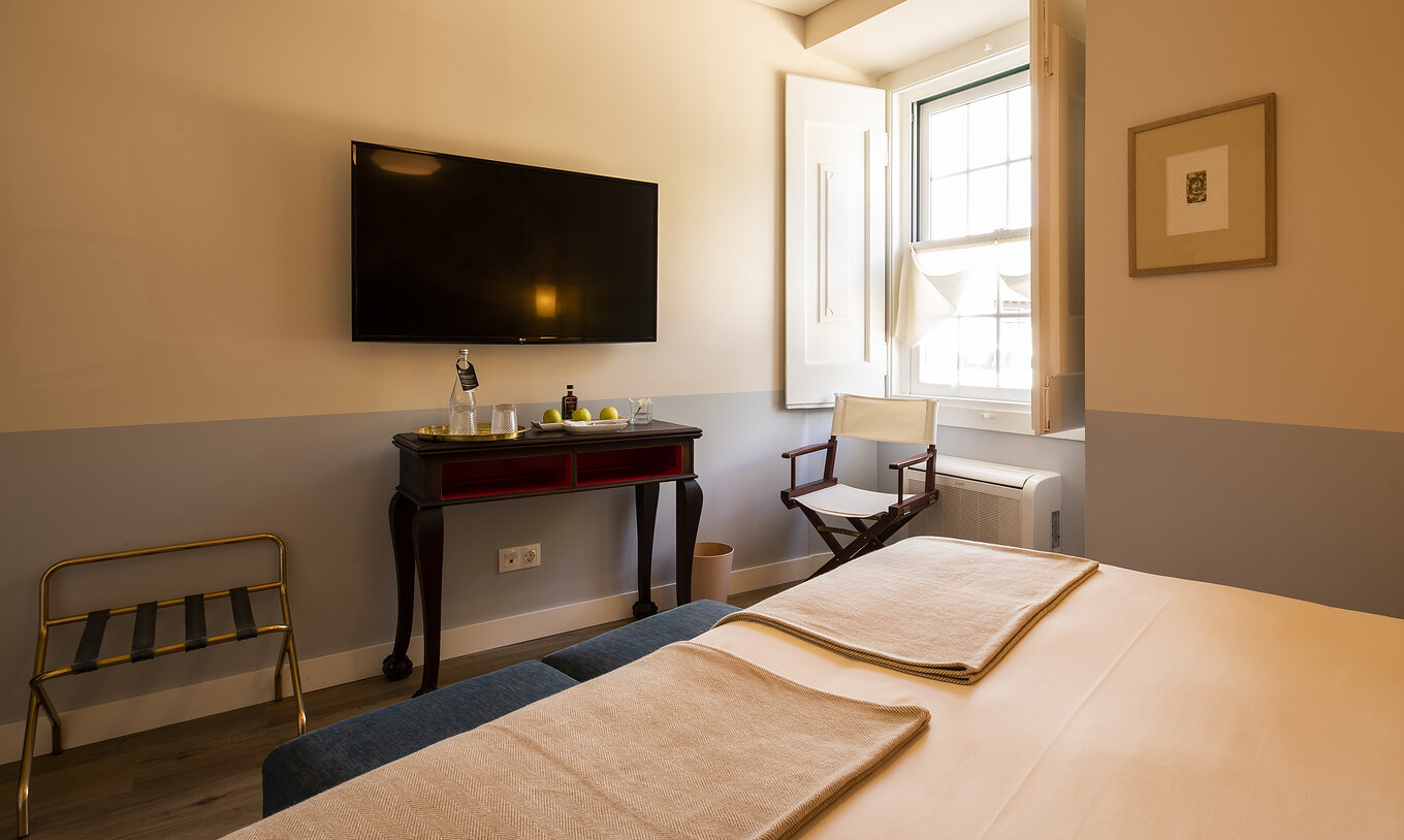 The Classic Room of The Pousada Vila Óbidos has a double bed and a television in front, a window, and a chair