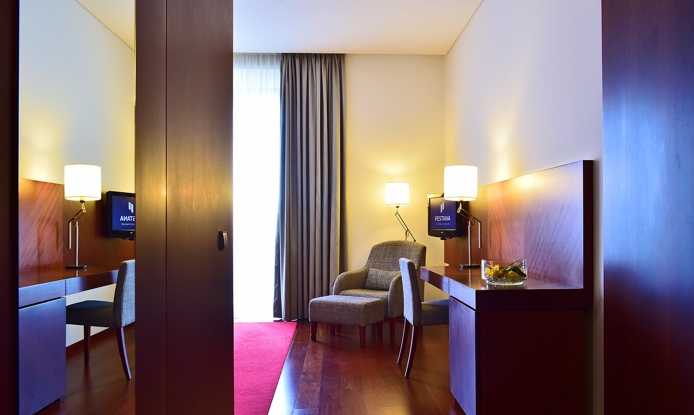 The Classic Room of the Pousada Viseu has a mirror, a wardrobe, desk, television and an armchair