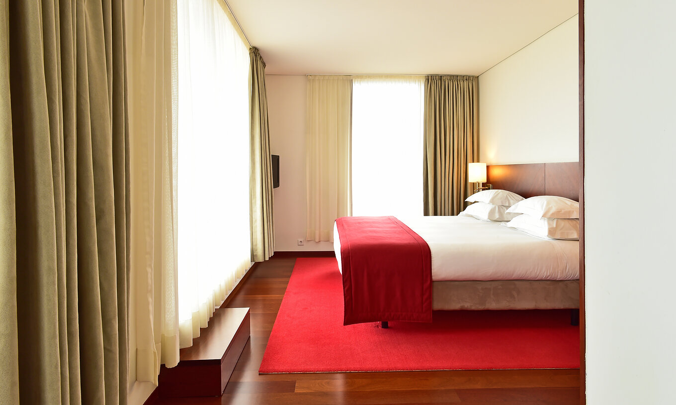 The Special Suite of the Pousada Viseu has a double bed, a lamp and two large windows with curtains