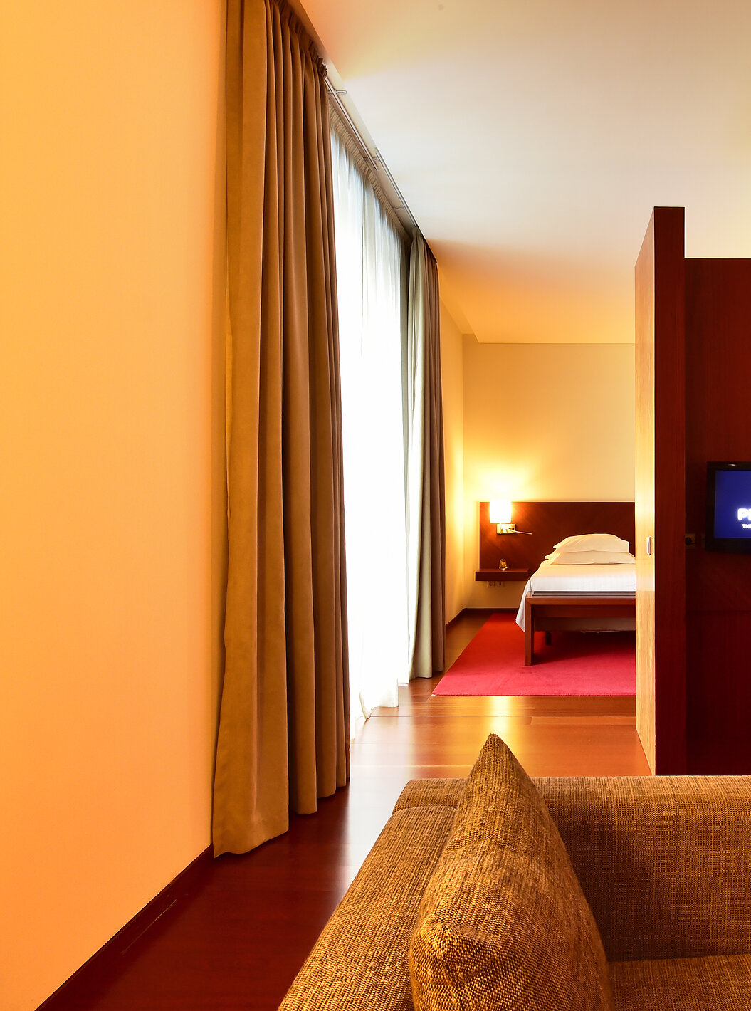The Standard Suite of the Pousada Viseu has a sofa, desk with lamp and chair, and a television