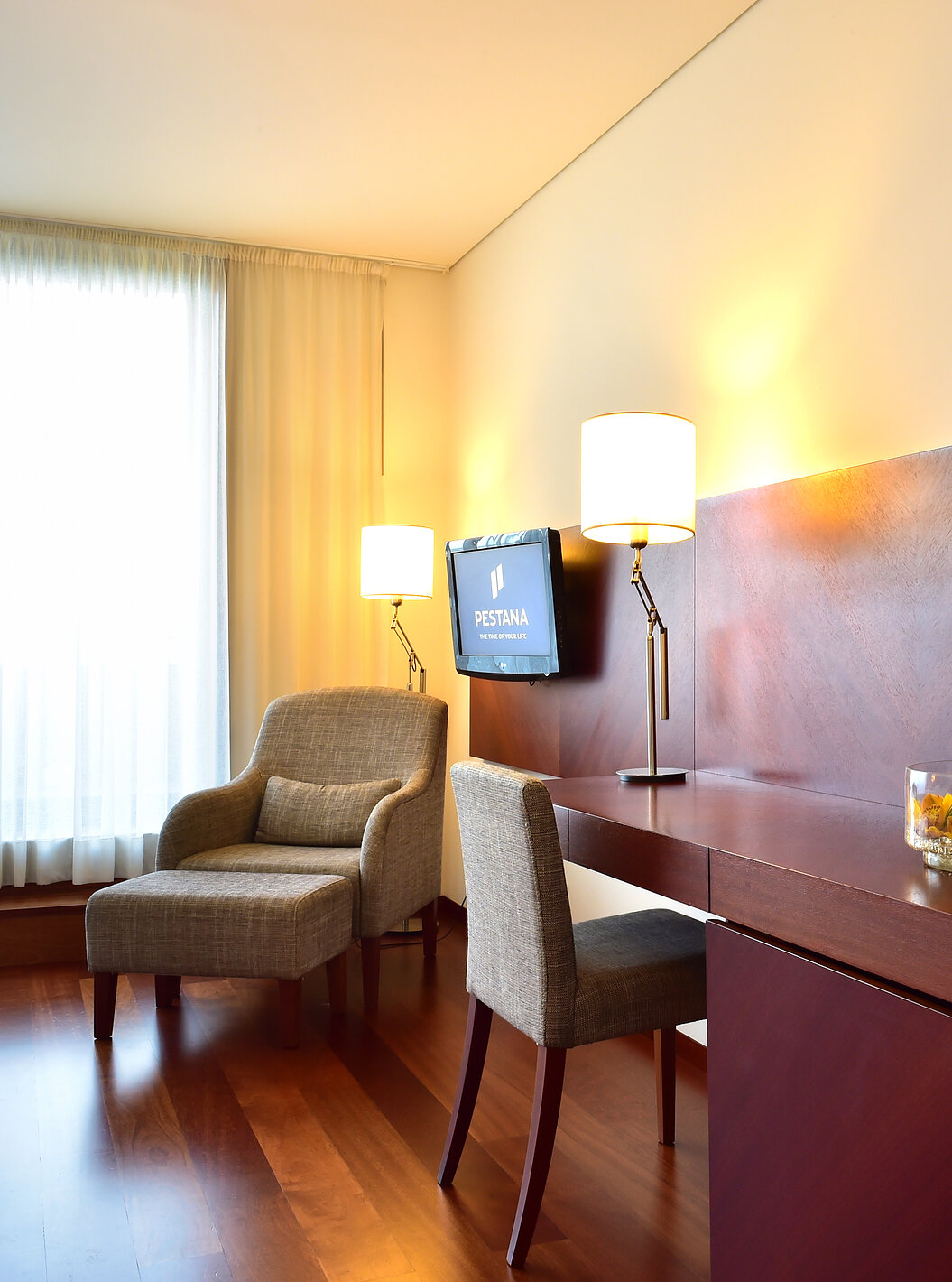 The Superior Room of the Pousada Viseu has a desk with chair and lamp, and an armchair beside