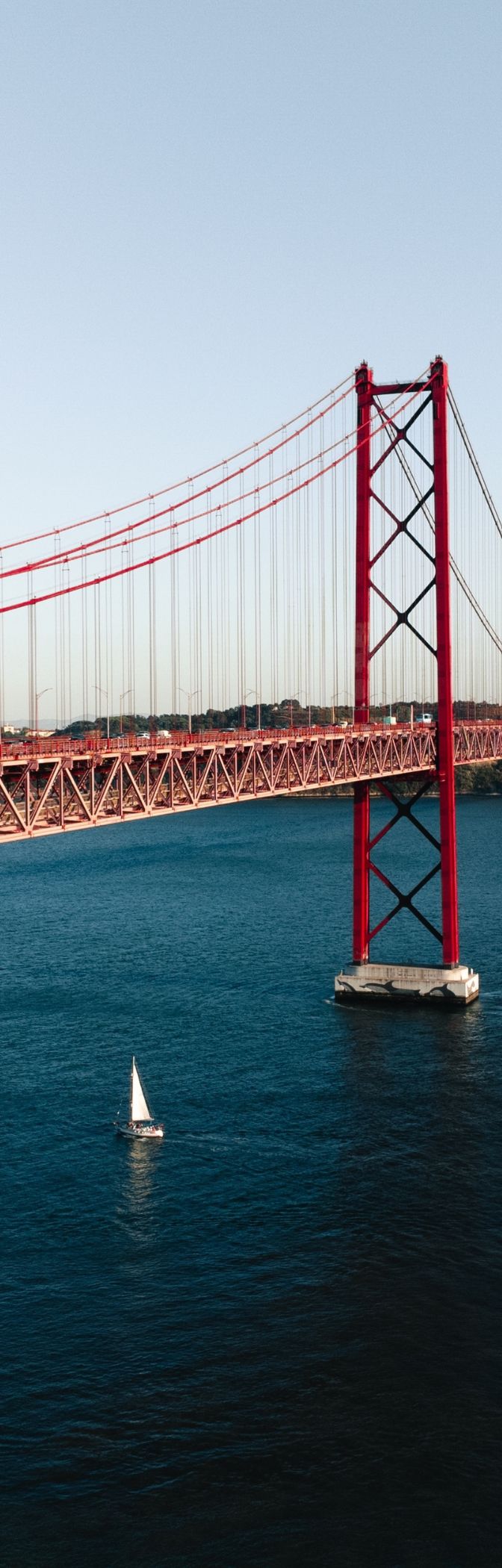 Panoramic view of the city of Lisbon, with the Tejo River featuring several boats and the 25 de Abril Bridge