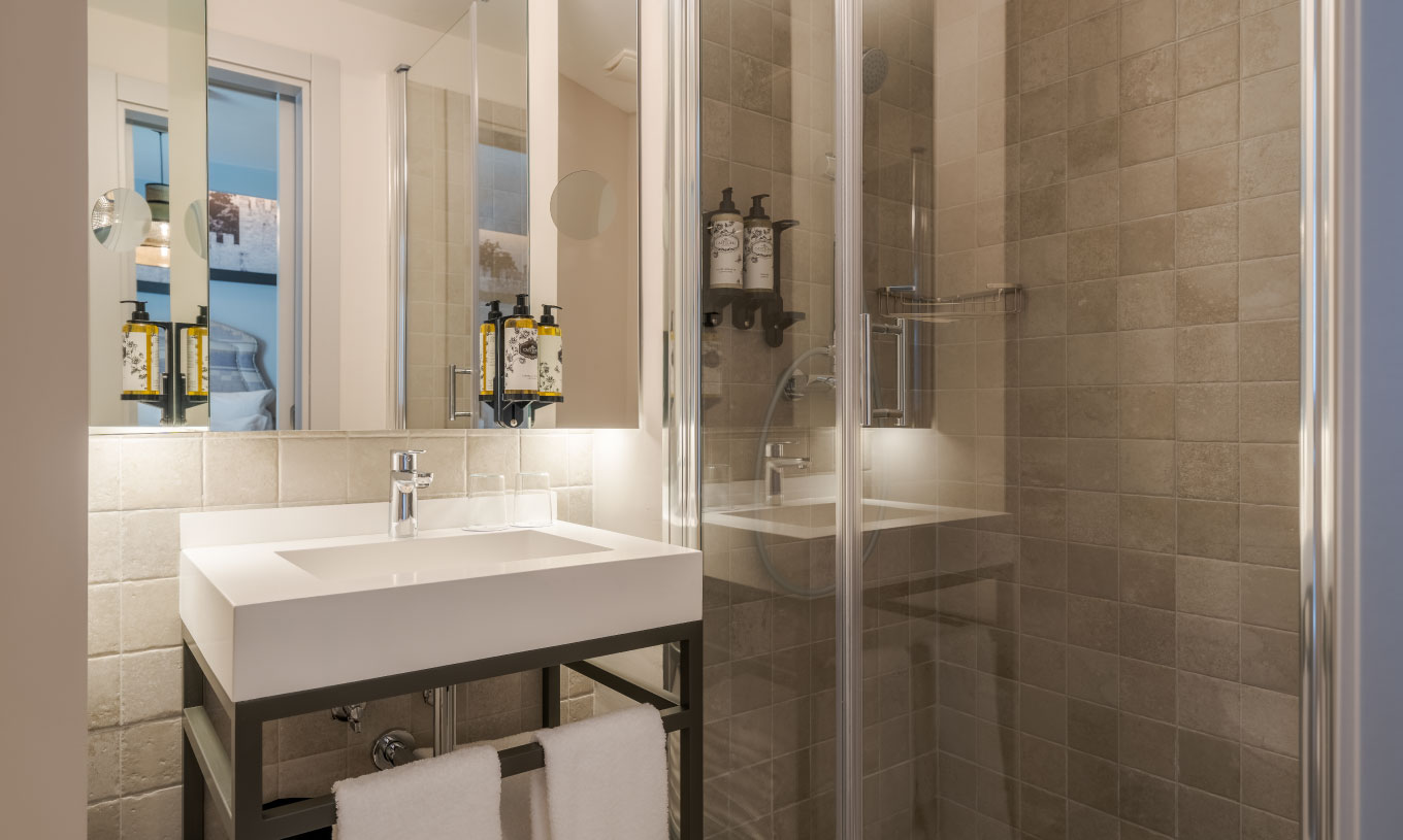 Cozy at Pousada Alfama has a modern bathroom with shower, white sink, white towels and mirror