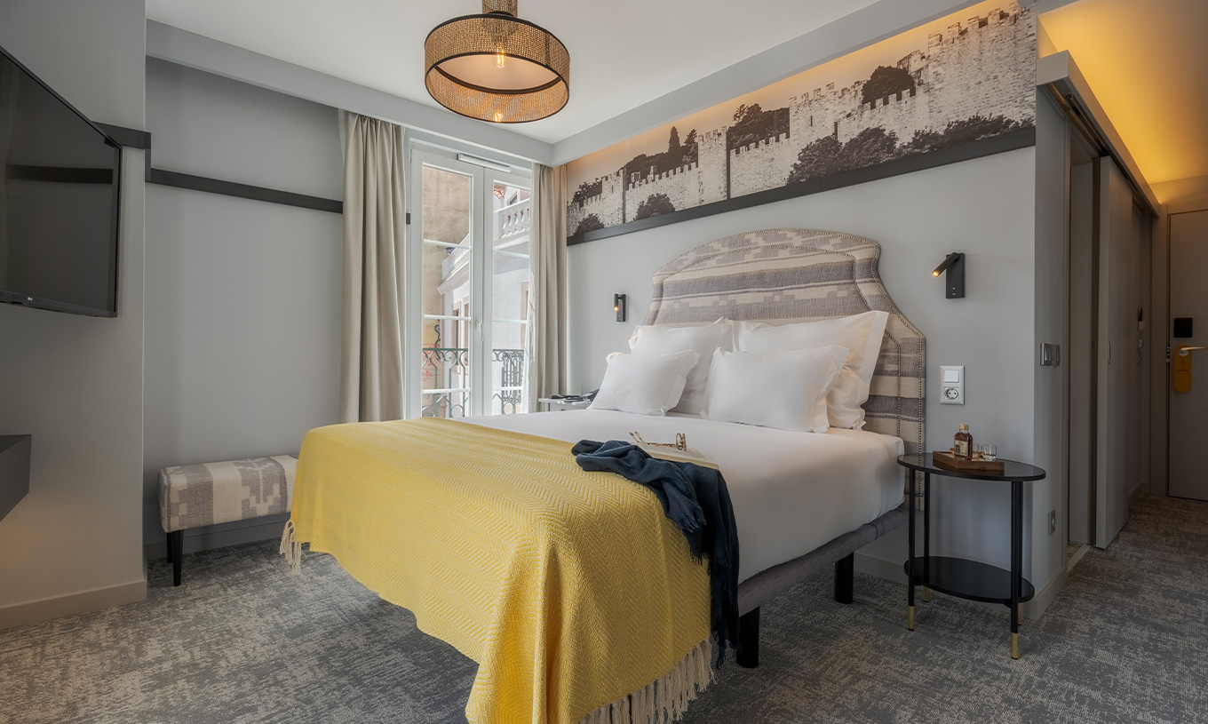 The Large Family Premium room at Pousada Alfama has a double bed in a spacious room decorated in yellow tones