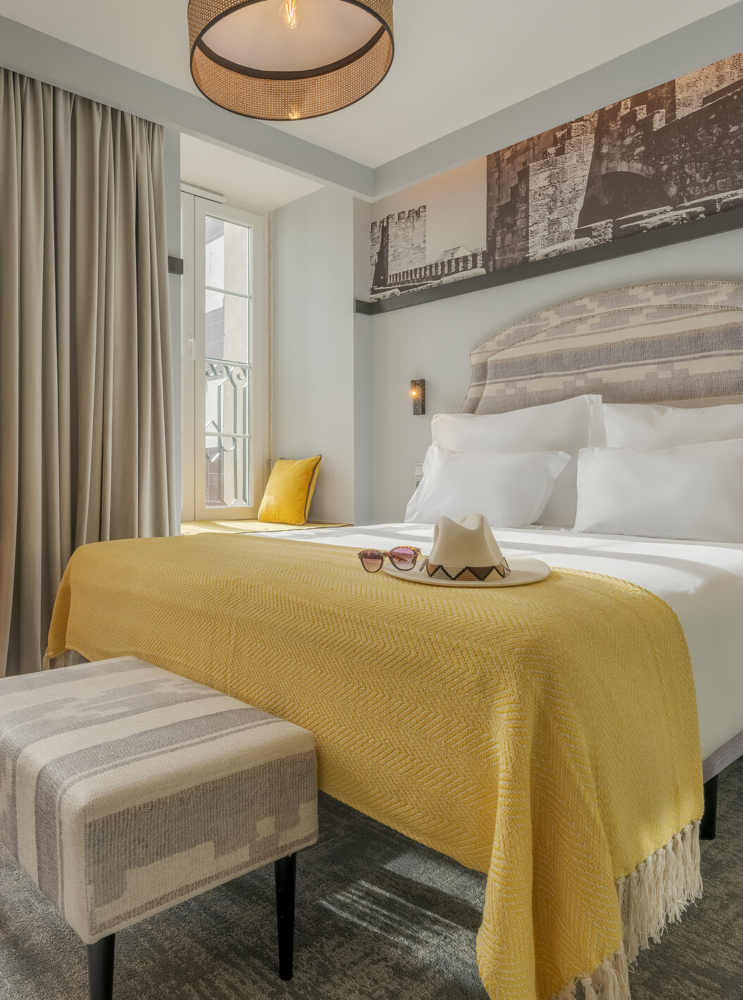 The Superior River at Pousada Alfama has a double bed with a small bench at the foot and a yellow armchair