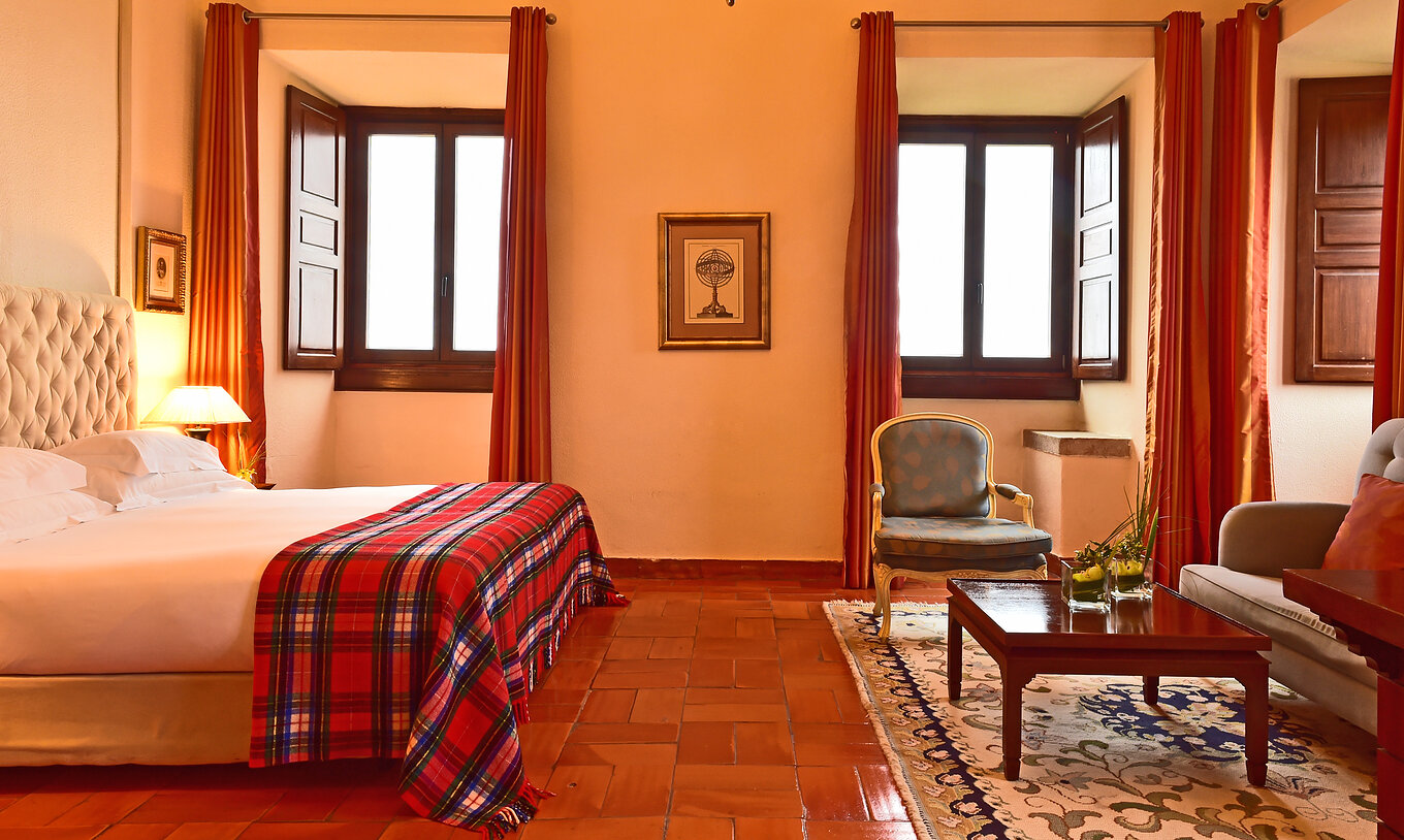 The Master Suite at Pousada Castelo Palmela has a double bed, two windows, a sofa, an armchair, and a wooden table
