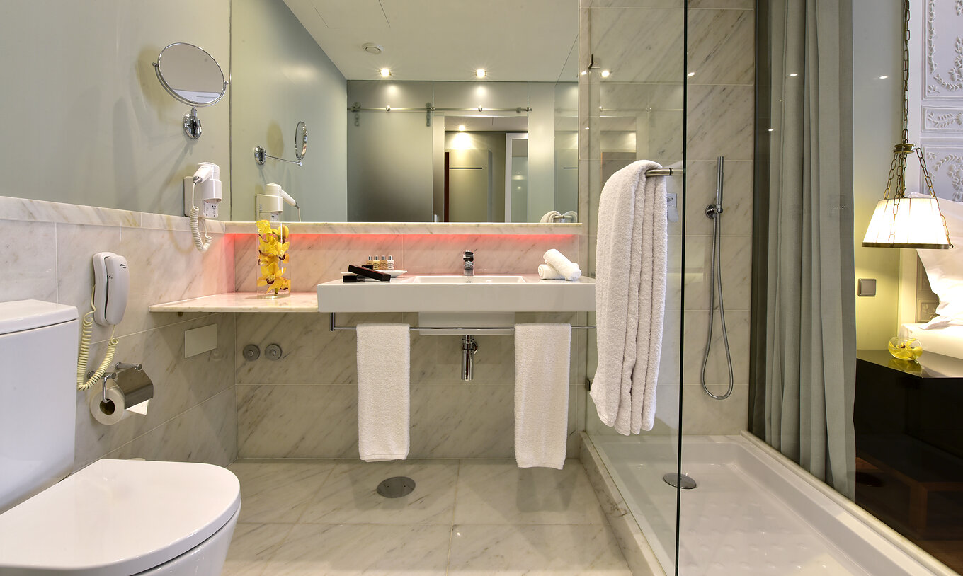 The Classic King Size Bed at Pousada Lisboa Praça do Comércio has a marble bathroom with a glass shower