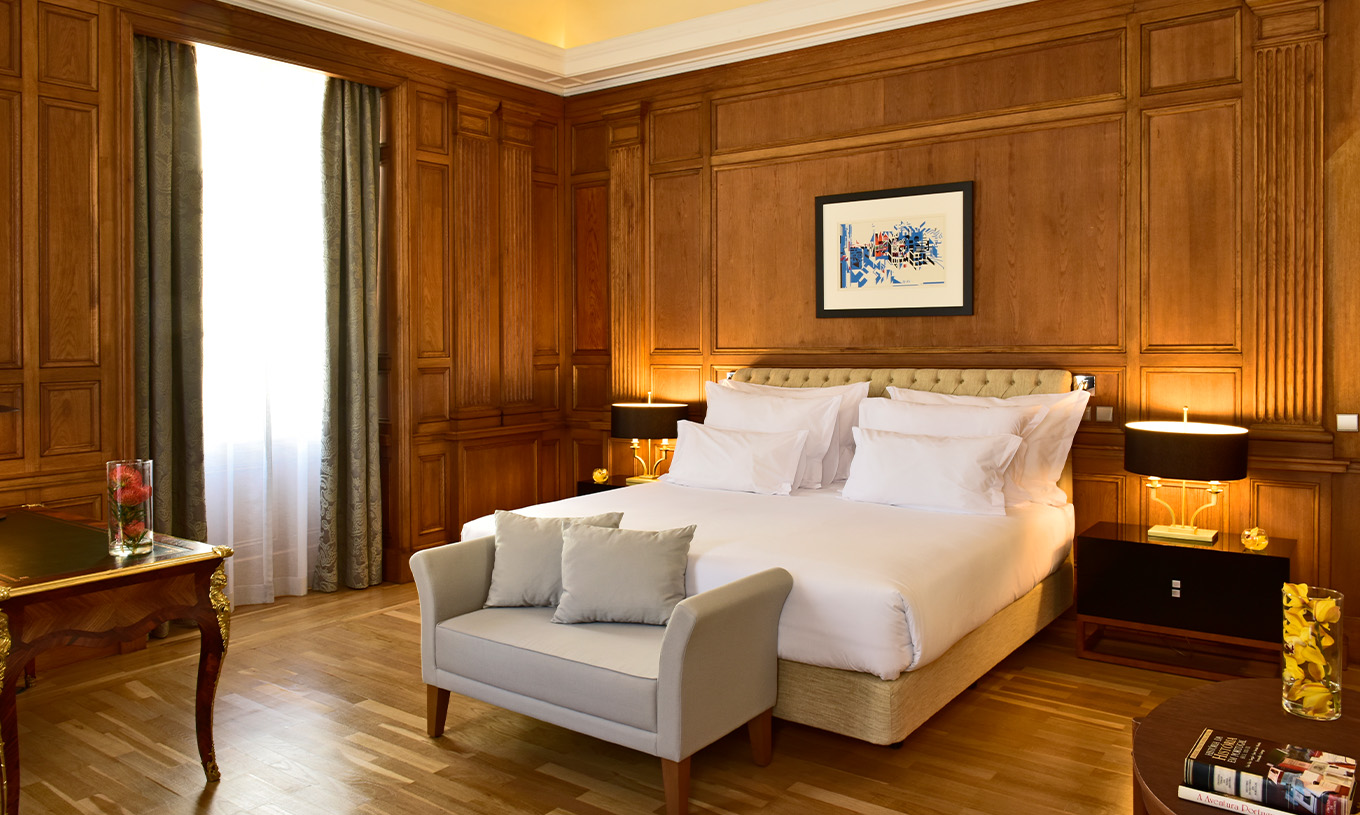 The Áurea Suite King Size Bed of The Pousada Lisboa Praça do Comércio has a double bed with a sofa at the foot and a window