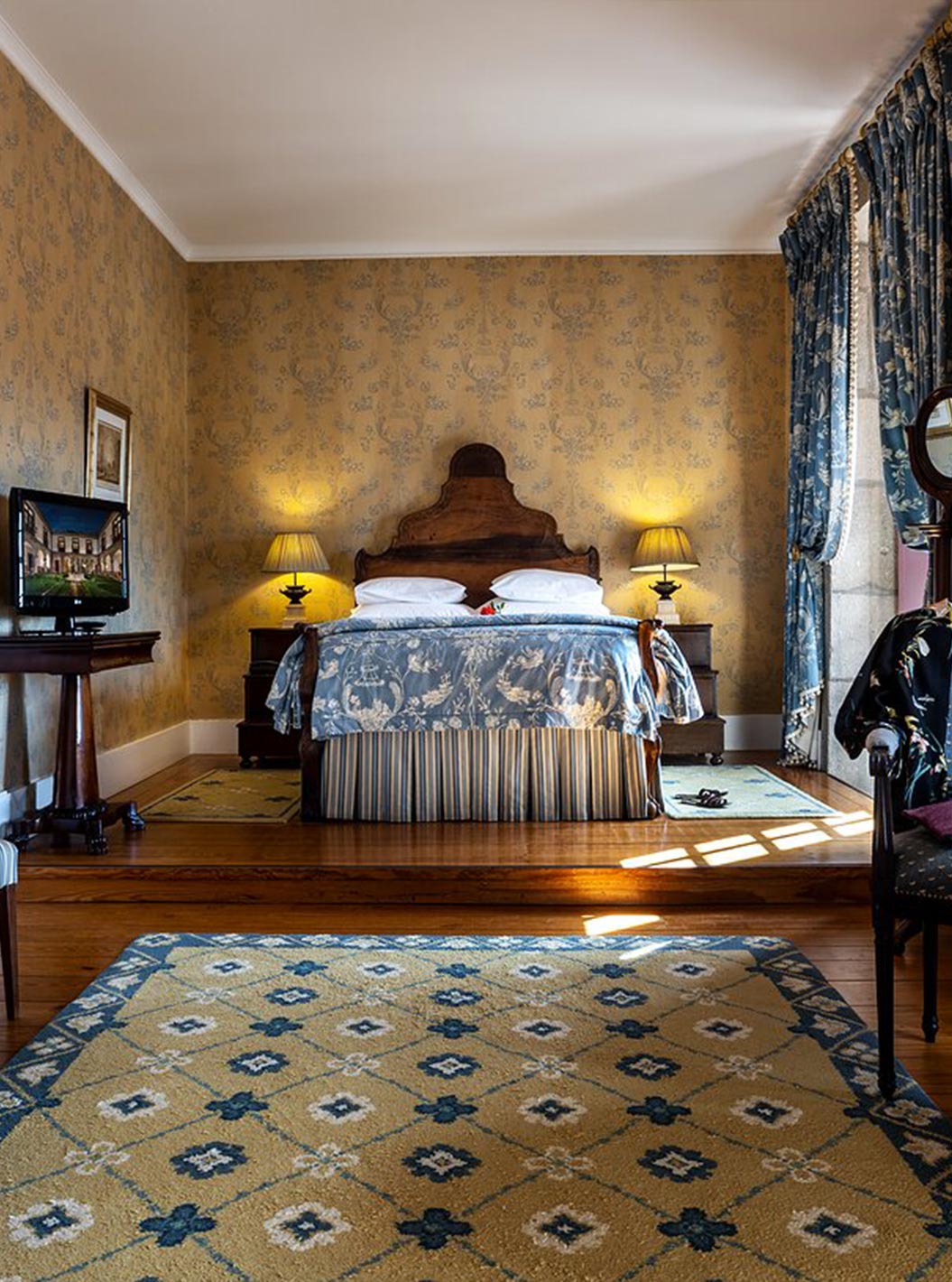 The Master Suite at Pousada Mosteiro Guimarães features blue tones, a double bed, table, chairs, and a dresser.