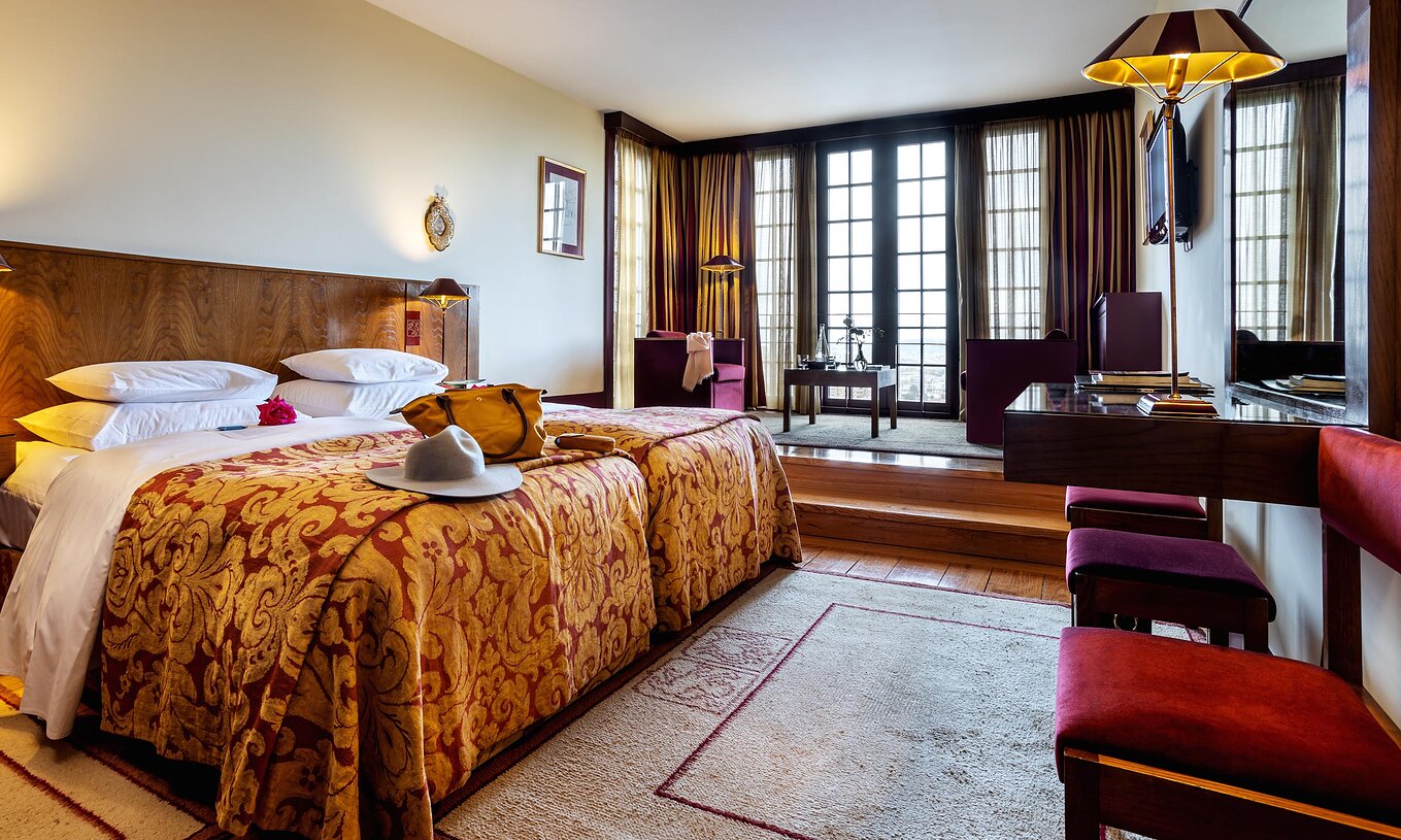 The Superior Room of The Pousada Mosteiro Guimarães has two separate beds, a television, and a large window