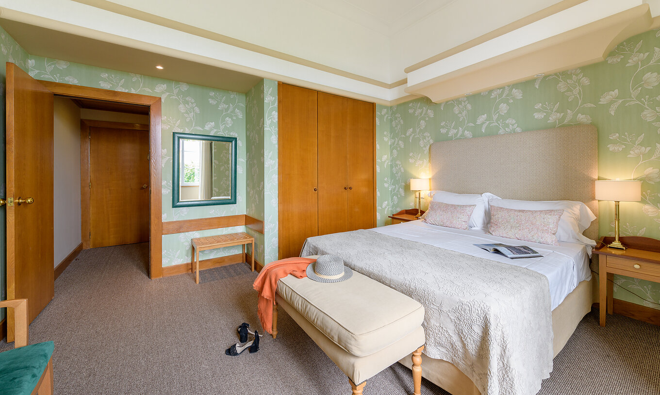 The Classic Room of The Pousada Viana do Castelo has walls decorated with flowers in green tones, a bed, and a wardrobe