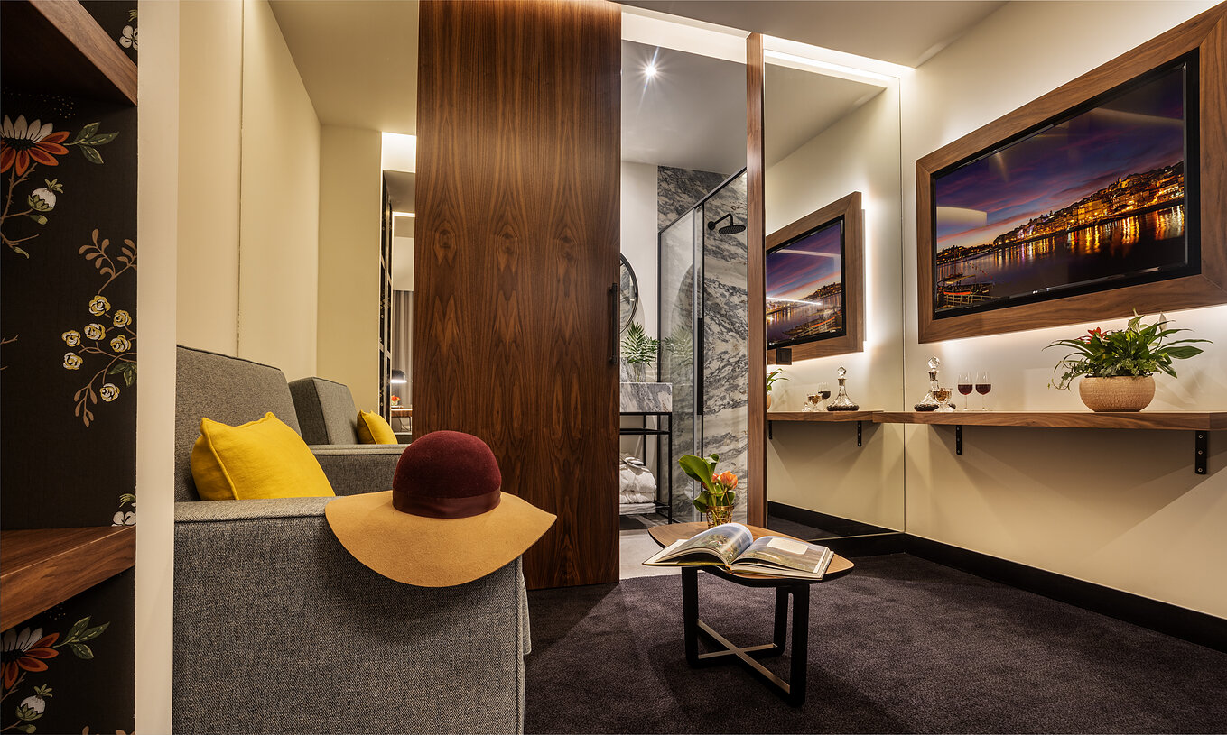 The Junior Suite of The Porto Inn - Rua das Flores has a sofa by the bathroom, with a TV in front